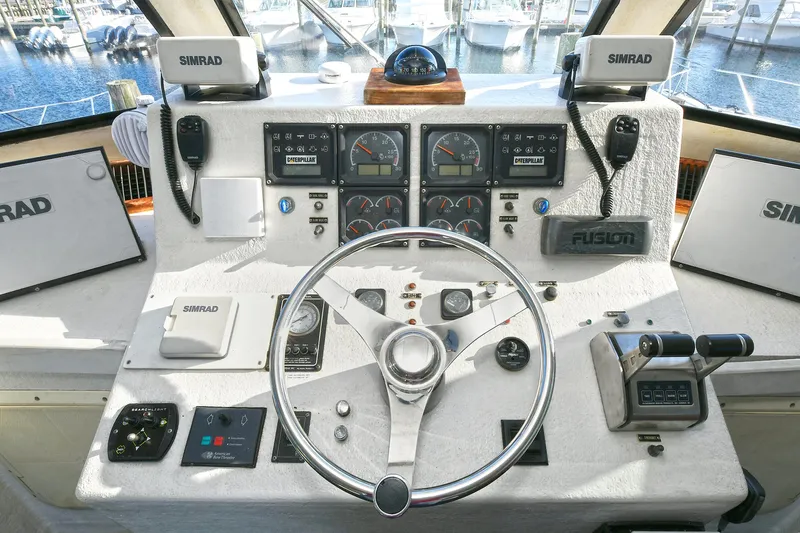 Journey Yacht Photos Pics Control panel of a 2000 Torres 48 Enclosed Bridge boat with navigation instruments and steering wheel.