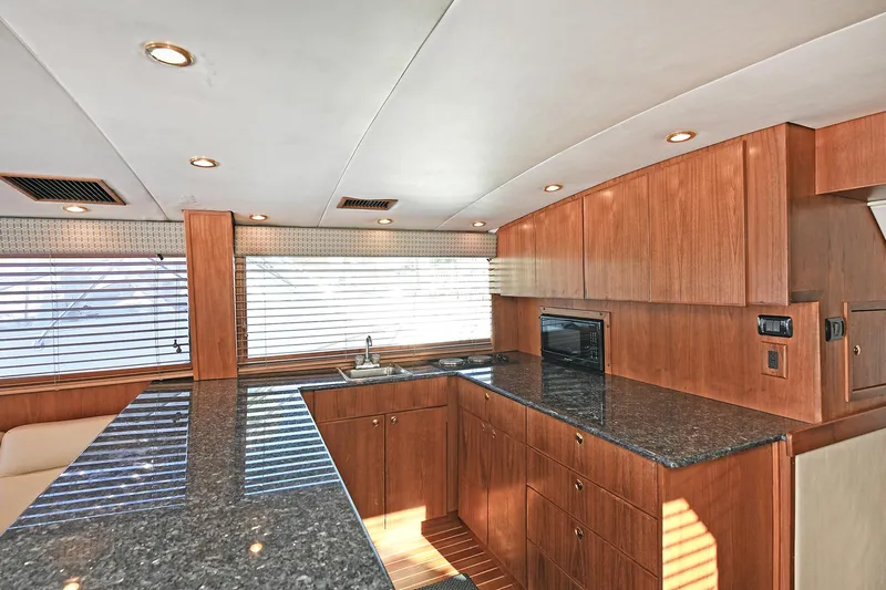 Journey Yacht Photos Pics Luxurious kitchen interior of 2000 Torres 48 Enclosed Bridge yacht with wood cabinetry and granite countertops.