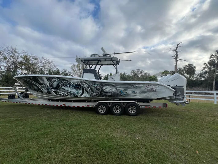  Yacht Photos Pics 2019 Yellowfin 36 Offshore boat with custom artwork on a trailer, parked on grass.