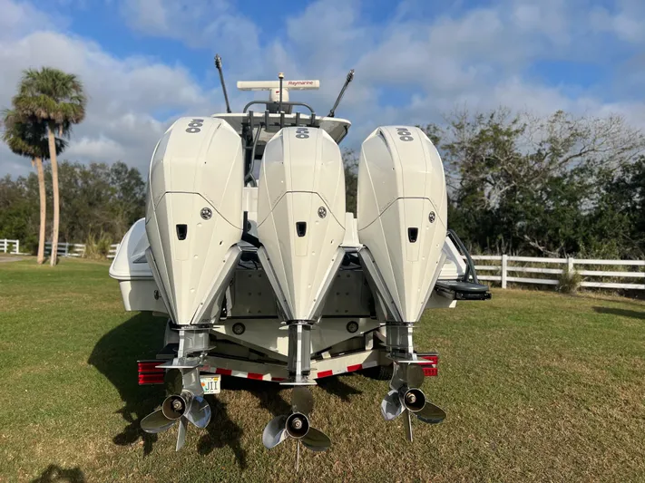  Yacht Photos Pics 2019 Yellowfin 36 Offshore boat with triple outboard engines on a grassy area.