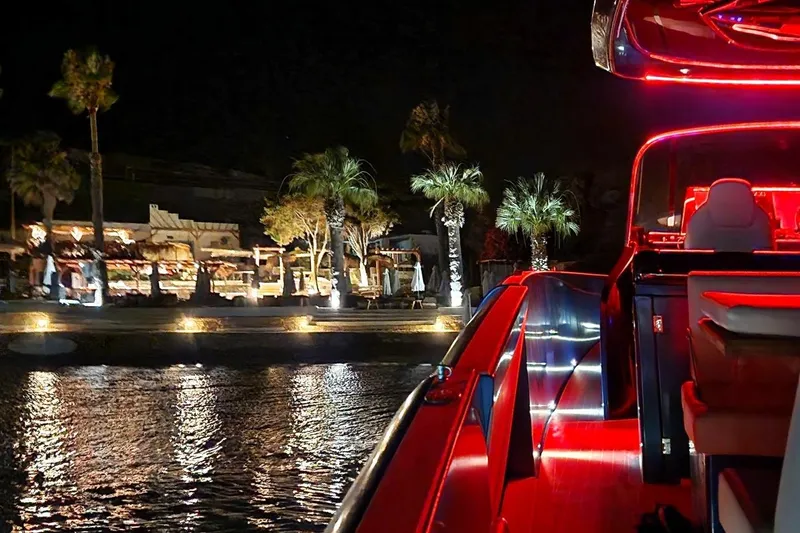 Aegean Infinity Yacht Photos Pics 2023 Solaris Power 44 Open yacht with vibrant red lighting at night near a lit waterfront.