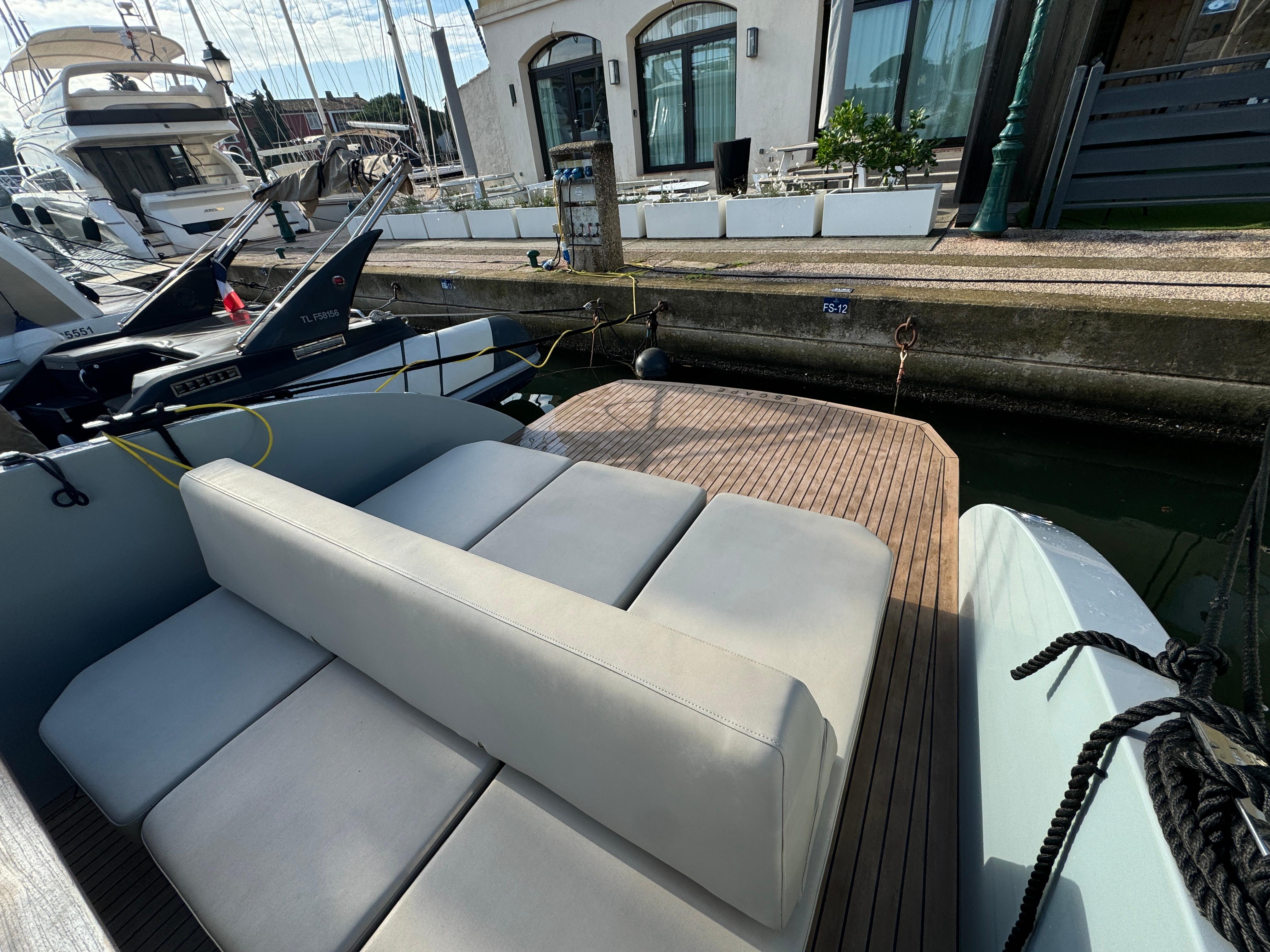 2022 Rand Escape 30 boat with sleek seating and wooden deck at a marina.