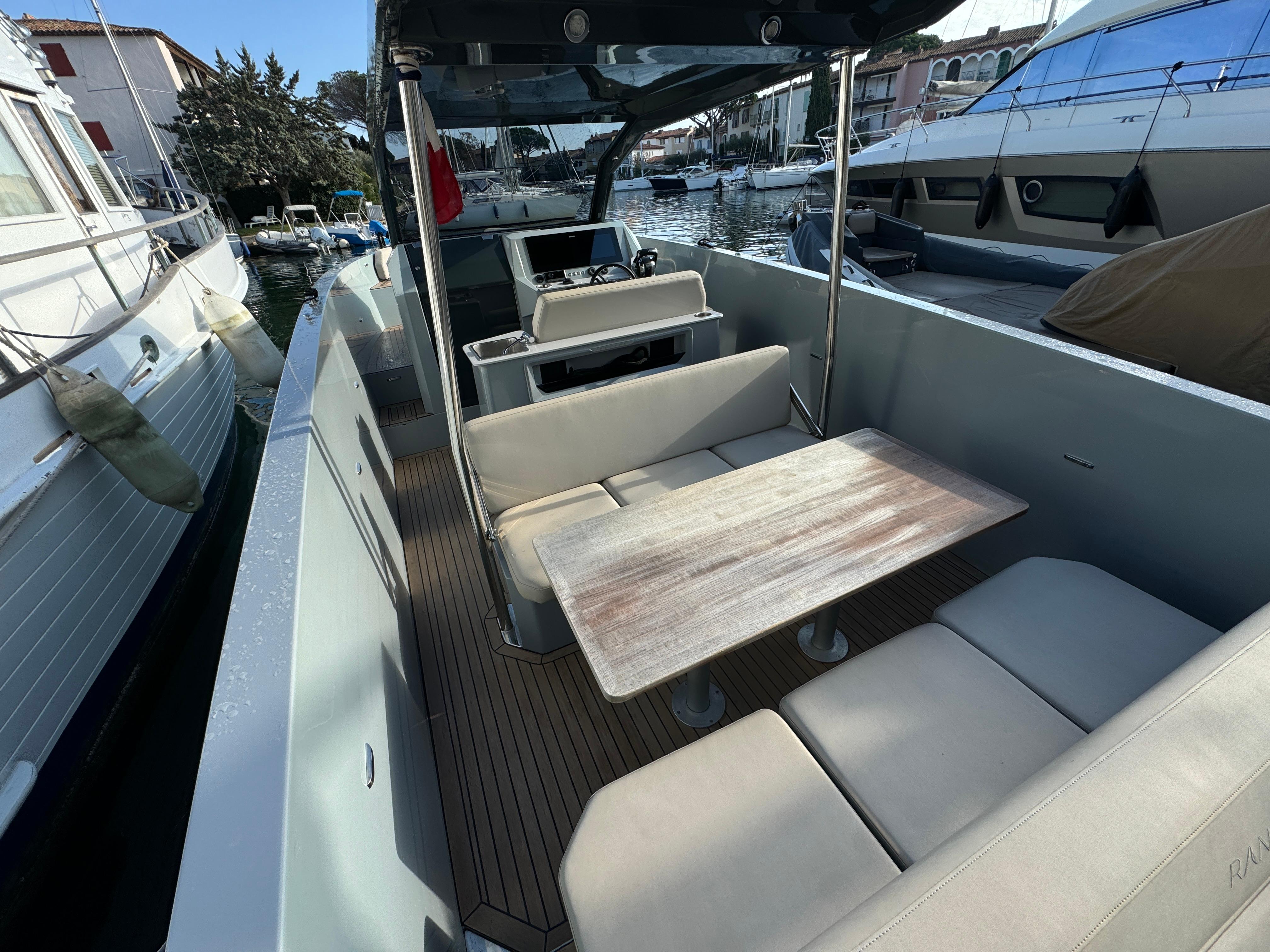2022 Rand Escape 30 boat interior with seating and table, docked at a marina.