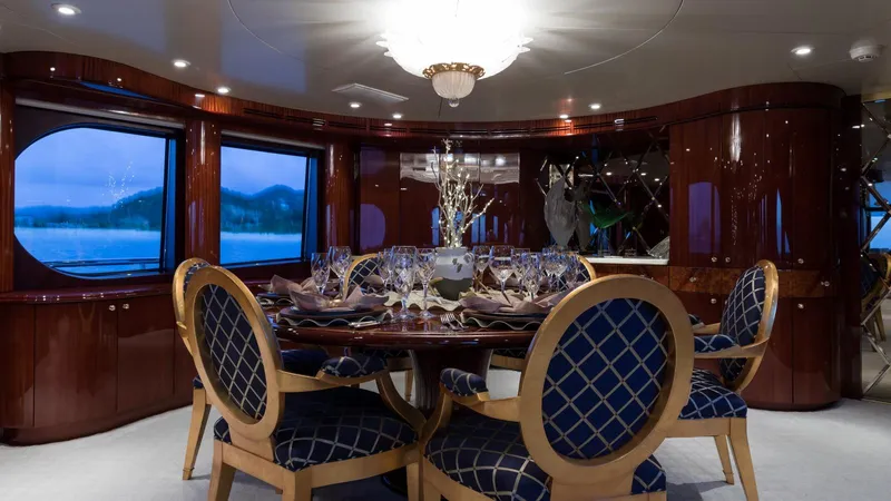 Touch Yacht Photos Pics Luxurious yacht dining room with elegant table setting, blue cushioned chairs, and polished wood interior.