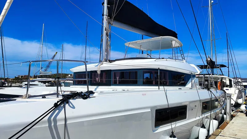  Yacht Photos Pics 2024 Lagoon 51 yacht docked at marina under clear blue sky.