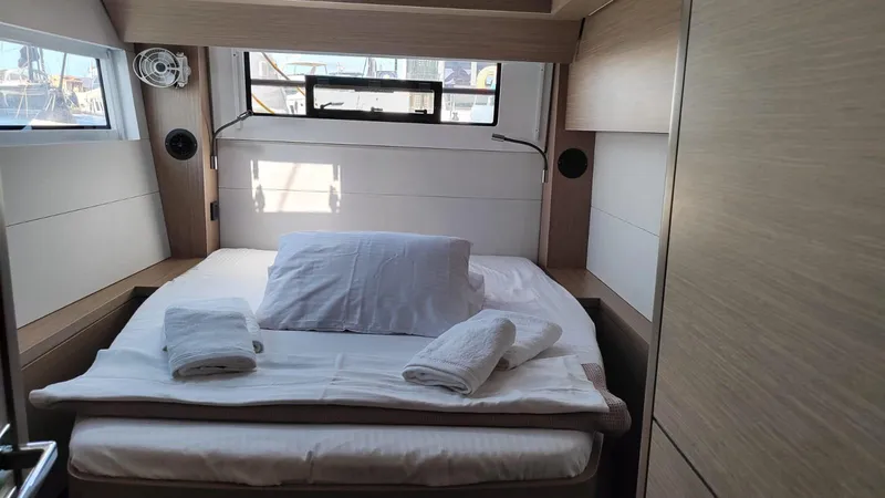  Yacht Photos Pics 2024 Lagoon 51 yacht cabin with neatly arranged bed and window view.