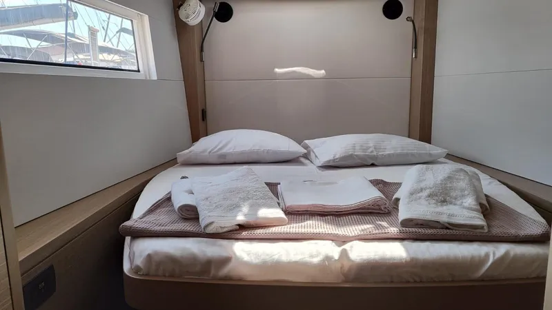  Yacht Photos Pics 2024 Lagoon 51 yacht cabin with neatly arranged bed and towels.