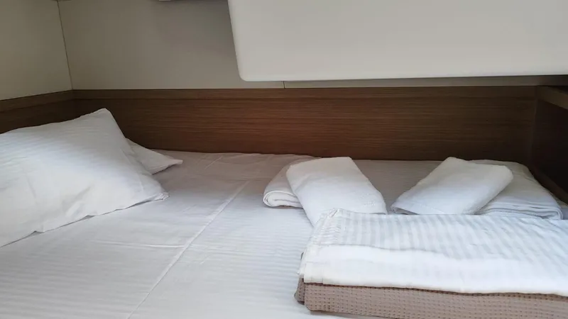  Yacht Photos Pics 2024 Lagoon 51 yacht cabin with neatly arranged bed and white linens.