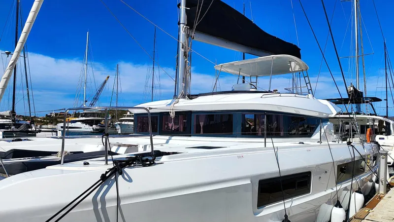  Yacht Photos Pics 2024 Lagoon 51 catamaran docked at marina under clear blue sky.