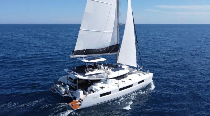  Yacht Photos Pics 2024 Lagoon 51 sailing catamaran cruising on open sea under clear blue sky.