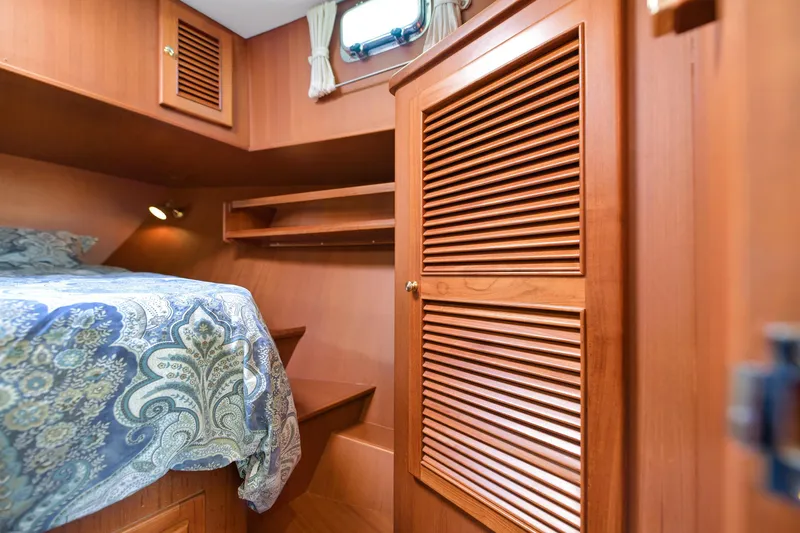 Island Harmony Yacht Photos Pics Cozy cabin interior of 2012 North Pacific NP 38 Sedan with wooden finishes and patterned bedding.