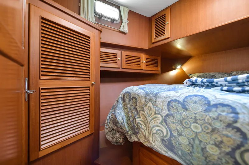 Island Harmony Yacht Photos Pics Cozy cabin interior of 2012 North Pacific NP 38 Sedan with wooden cabinetry and patterned bedding.