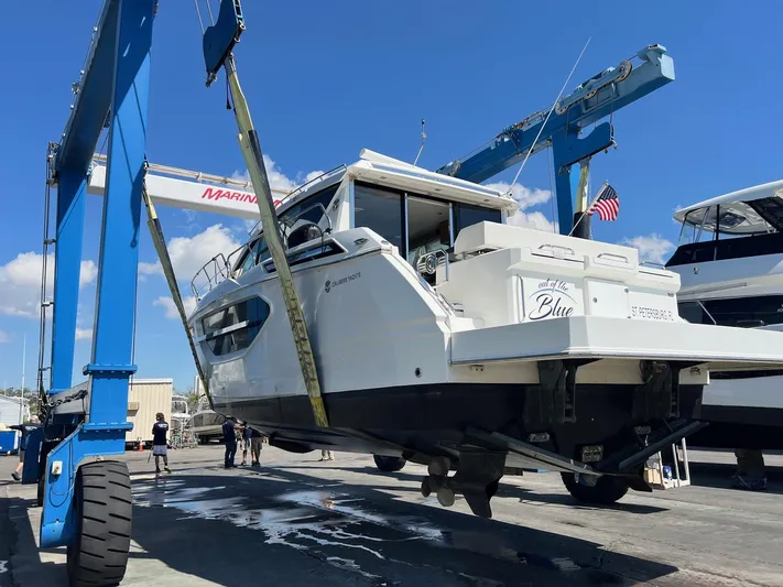  Yacht Photos Pics 2018 Cruisers Yachts 42 Cantius being lifted at a marina under a clear blue sky.