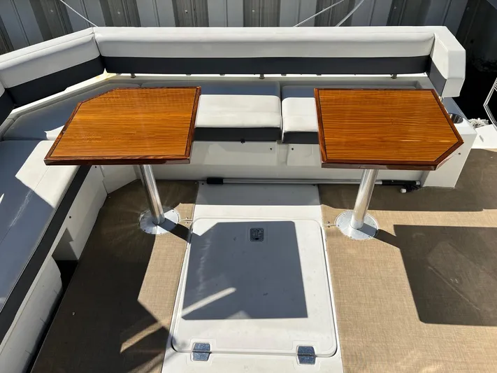  Yacht Photos Pics 2018 Cruisers Yachts 42 Cantius cockpit with dual wooden tables and cushioned seating.