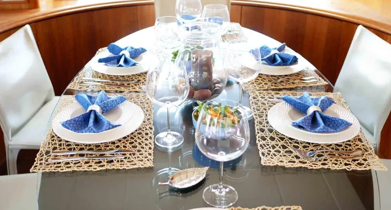  Yacht Photos Pics Elegant dining setup on 2006 Couach 3000 Fly yacht with blue napkins and glassware.