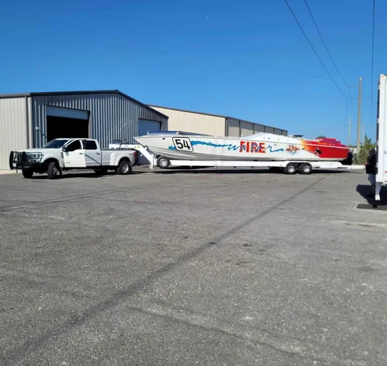  Yacht Photos Pics Truck towing 1994 Apache 47 Fire Water boat near warehouse.