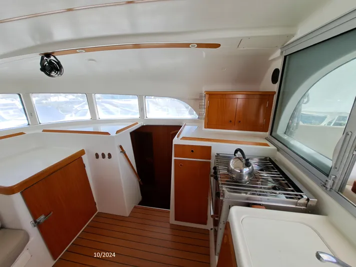 Tortuga Yacht Photos Pics Interior of 2001 Lagoon 380 catamaran with wooden cabinetry and compact kitchen area.