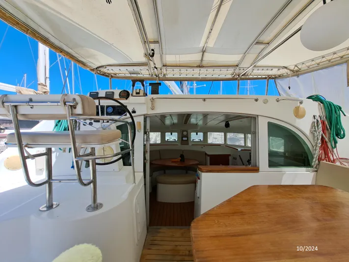 Tortuga Yacht Photos Pics 2001 Lagoon 380 catamaran interior with seating, helm, and wooden table under canopy.