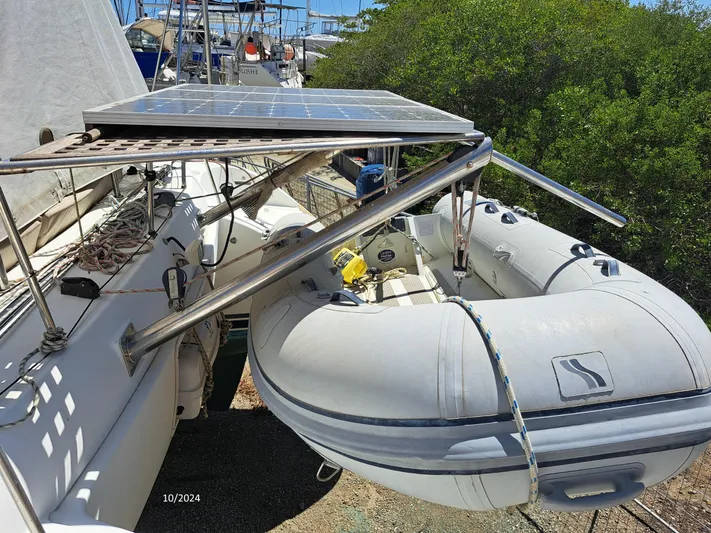 Tortuga Yacht Photos Pics Lagoon 380 catamaran with solar panels and inflatable dinghy, docked near lush greenery.