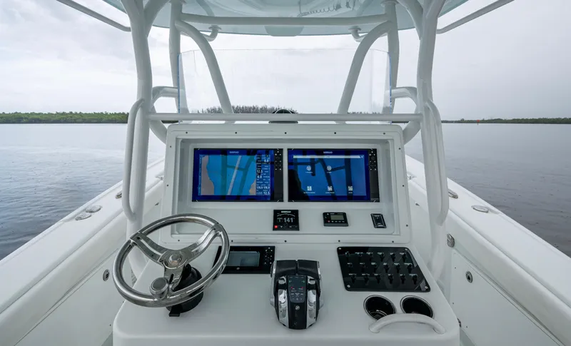  Yacht Photos Pics 2018 Yellowfin 36 Offshore boat dashboard with navigation screens and steering wheel on calm water.
