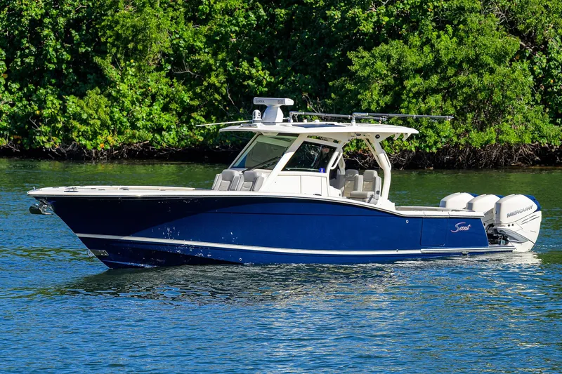 W/seakeeper Yacht Photos Pics 2023 Scout 355 LXF boat cruising on a serene waterway with lush greenery.