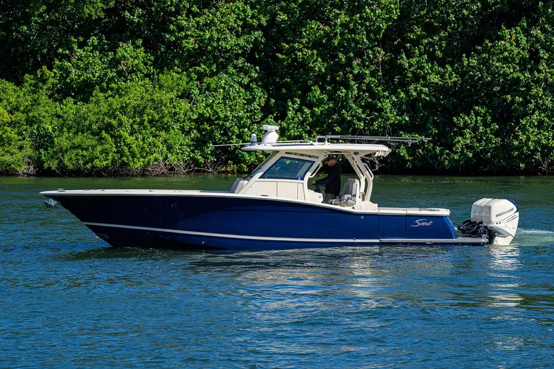 W/seakeeper Yacht Photos Pics 2023 Scout 355 LXF boat cruising on a serene waterway with lush greenery.