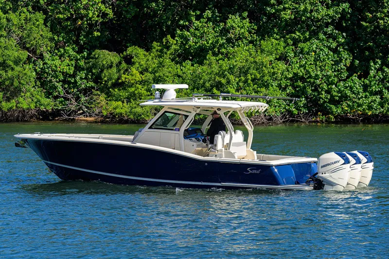 W/seakeeper Yacht Photos Pics 2023 Scout 355 LXF boat cruising on a serene lake with lush green background.