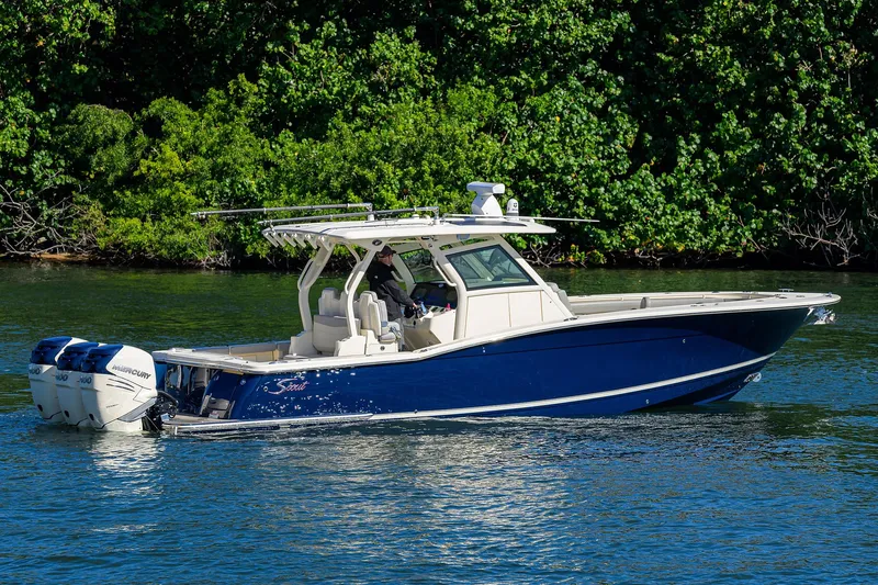 W/seakeeper Yacht Photos Pics 2023 Scout 355 LXF boat on water, blue hull, lush green background.