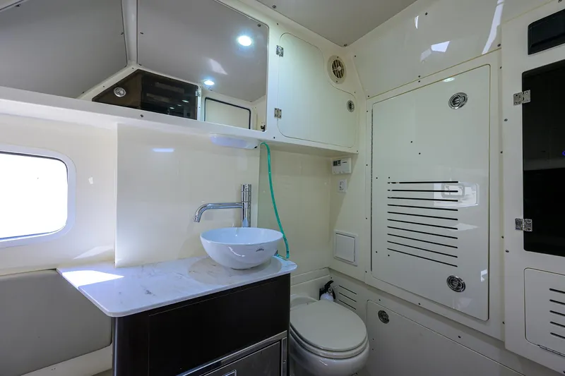 W/seakeeper Yacht Photos Pics 2023 Scout 355 LXF boat bathroom with modern sink, toilet, and storage cabinets.
