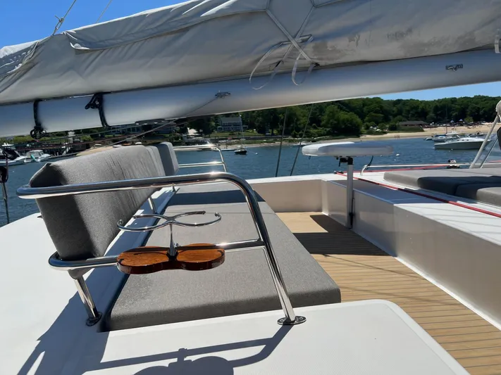 Tri It Yacht Photos Pics Luxurious NEEL 51 yacht deck with cushioned seating, overlooking serene waters and lush greenery.