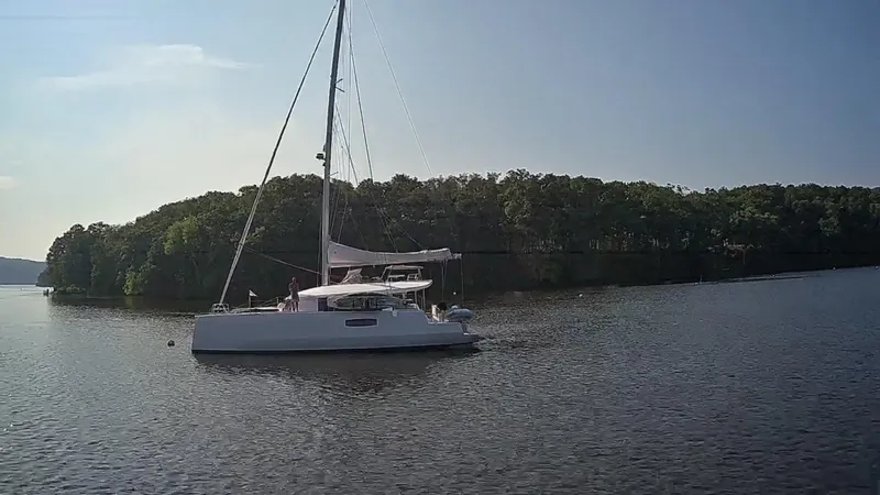 Tri It Yacht Photos Pics Sailing yacht NEEL 51, 2018 model, cruising on a calm lake near a forested shoreline.
