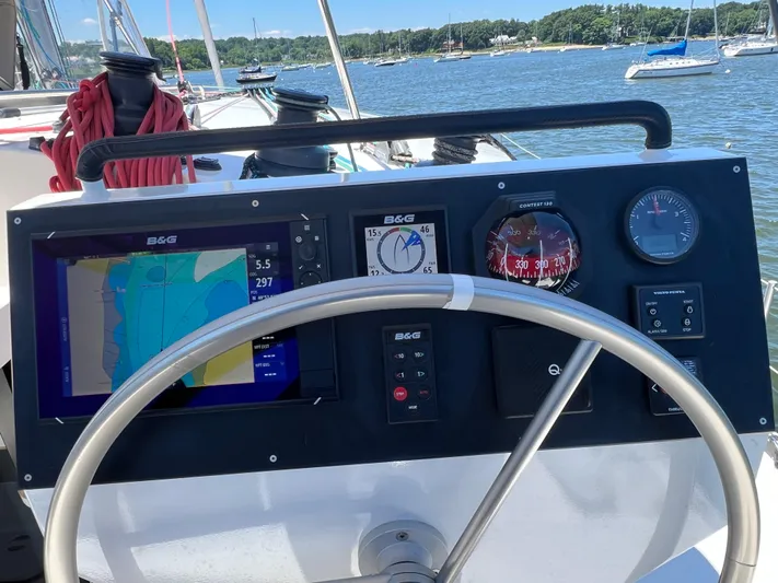 Tri It Yacht Photos Pics Steering console of a 2018 NEEL 51 trimaran with navigation instruments and a scenic marina view.
