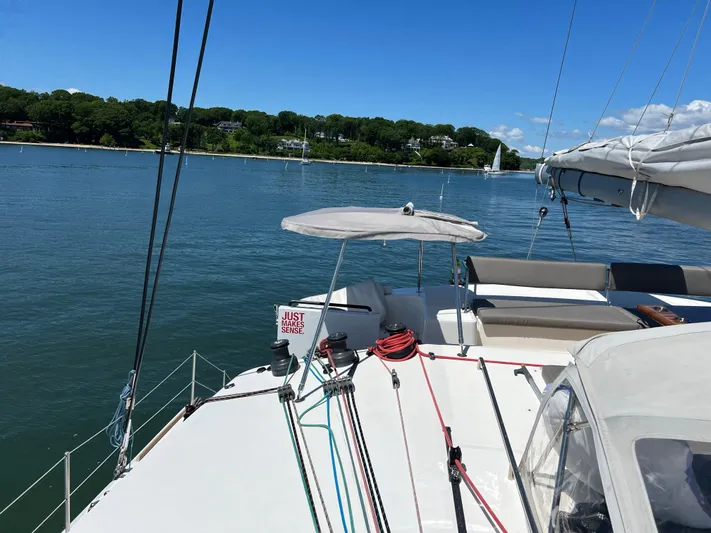 Tri It Yacht Photos Pics Trimaran NEEL 51 sailing on calm waters, 2018 model, with clear blue sky and shoreline view.