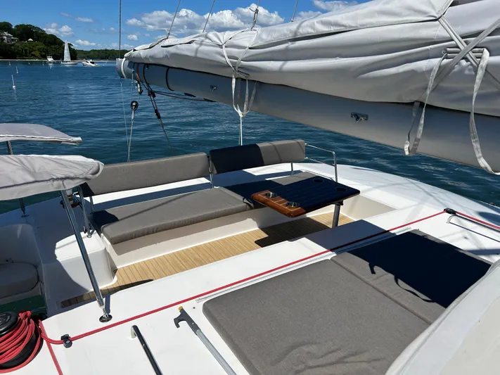 Tri It Yacht Photos Pics Spacious deck of 2018 NEEL 51 trimaran with seating and table, under clear blue skies.