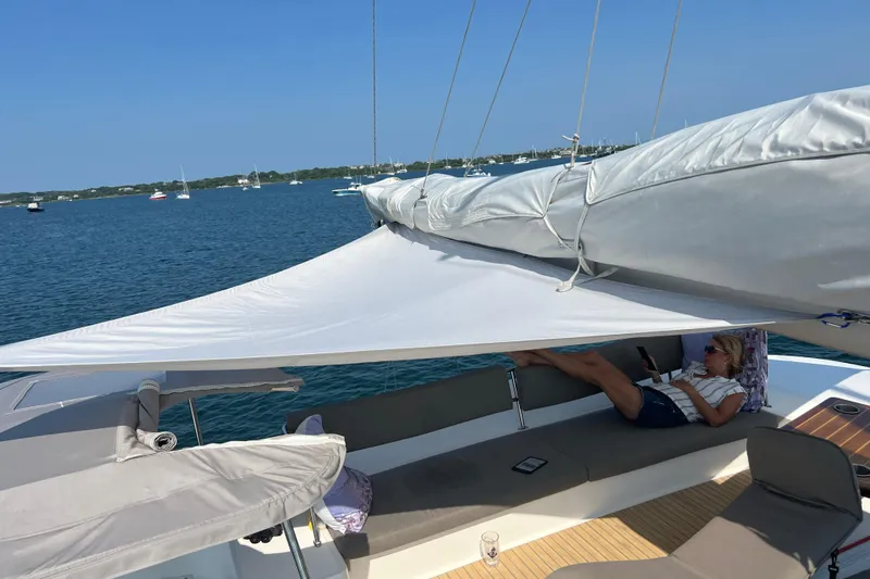 Tri It Yacht Photos Pics Woman relaxing on a 2018 NEEL 51 trimaran, enjoying a sunny day at sea.
