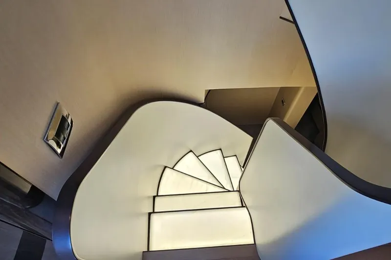  Yacht Photos Pics Curved staircase inside 2022 Azimut Grande 32 Metri yacht, featuring modern design and lighting.
