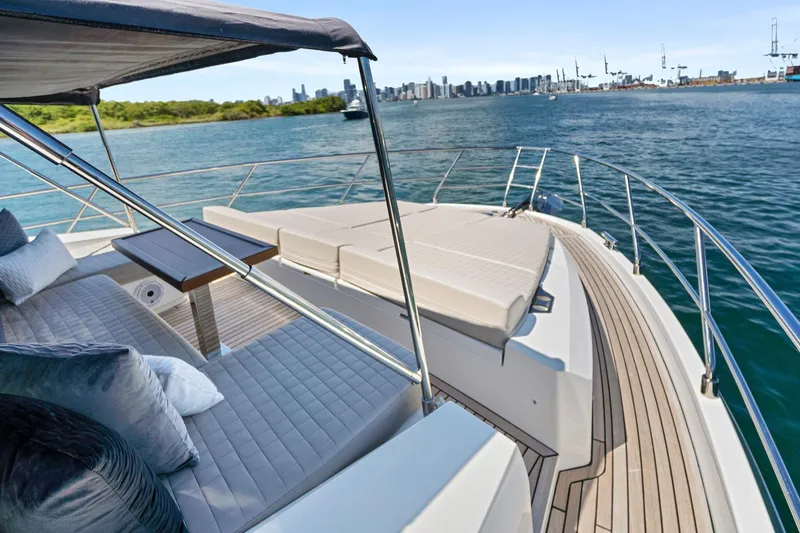 Smile Yacht Photos Pics 2023 Astondoa 66 Flybridge yacht with luxurious deck seating and scenic waterfront view.