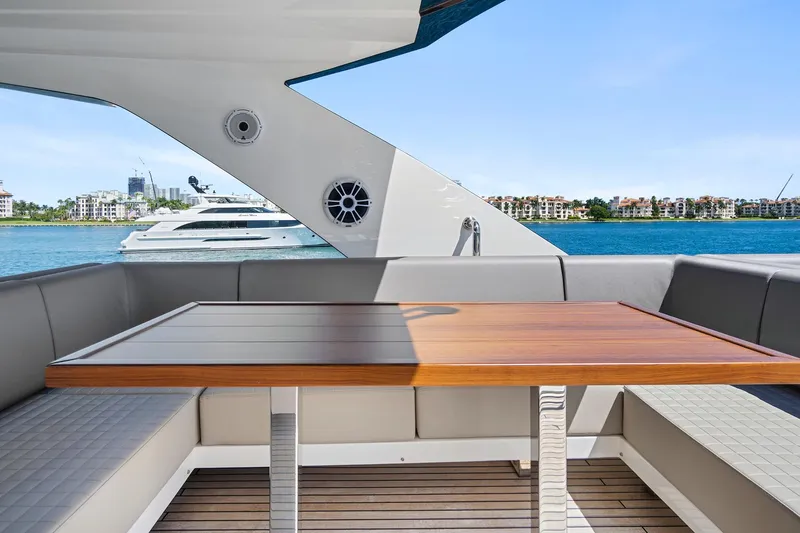 Smile Yacht Photos Pics Astondoa 66 Flybridge 2023 yacht deck with wooden table and waterfront view.