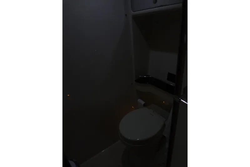 Dream Catcher Yacht Photos Pics Dimly lit bathroom interior of 2010 Formula 45 Yacht, featuring a toilet and storage space.