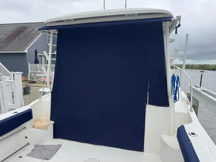  Yacht Photos Pics 2019 Boston Whaler 315 Conquest boat with blue canvas cover, docked near waterfront homes.