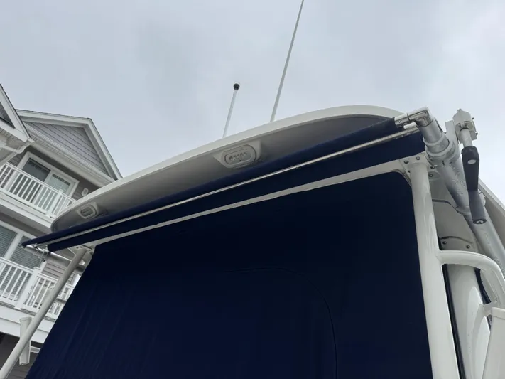 Yacht Photos Pics 2019 Boston Whaler 315 Conquest boat with blue canopy, docked near a house.