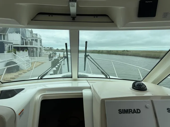  Yacht Photos Pics 2019 Boston Whaler 315 Conquest cockpit view with waterfront houses and Simrad navigation system.