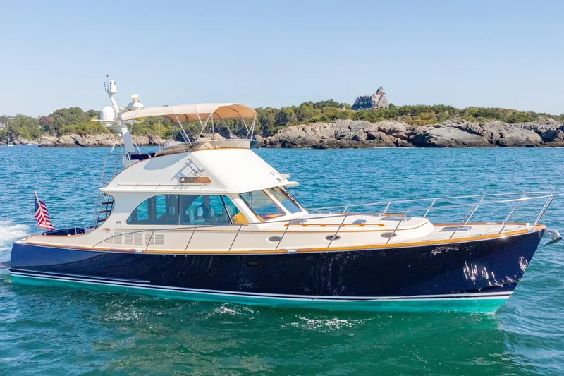 Virginia Yacht Photos Pics 2013 Hinckley Talaria 48 Flybridge yacht cruising on blue ocean near rocky shoreline.