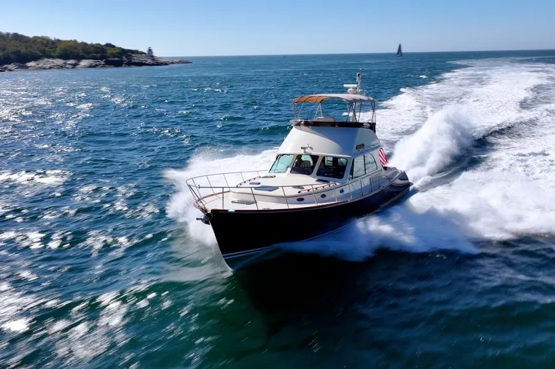 Virginia Yacht Photos Pics 2013 Hinckley Talaria 48 Flybridge cruising on open sea near rocky coastline.