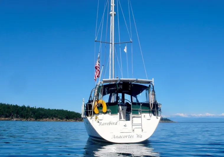 Rarebird Yacht Photos Pics 2004 Beneteau 393 sailboat on calm water, clear sky, rear view.