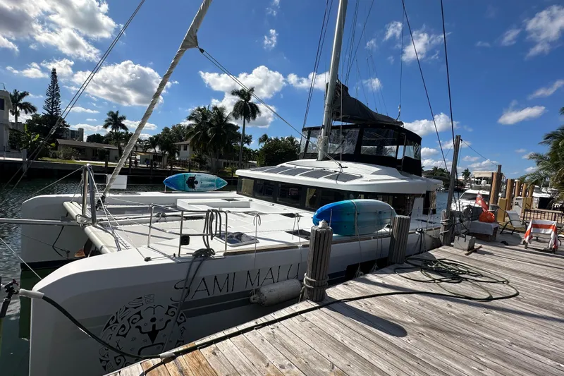 Sami Malu Yacht Photos Pics 2017 Lagoon 52 F catamaran docked under a sunny sky with palm trees.
