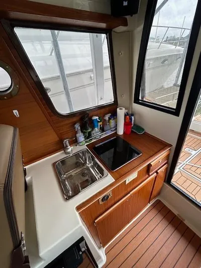  Yacht Photos Pics 2023 Ranger Tugs R23 interior with compact kitchen, sink, and wooden cabinetry.