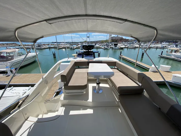 Inconseavable Yacht Photos Pics 2014 Marquis 500 Sport Bridge yacht in harbor with seating area.