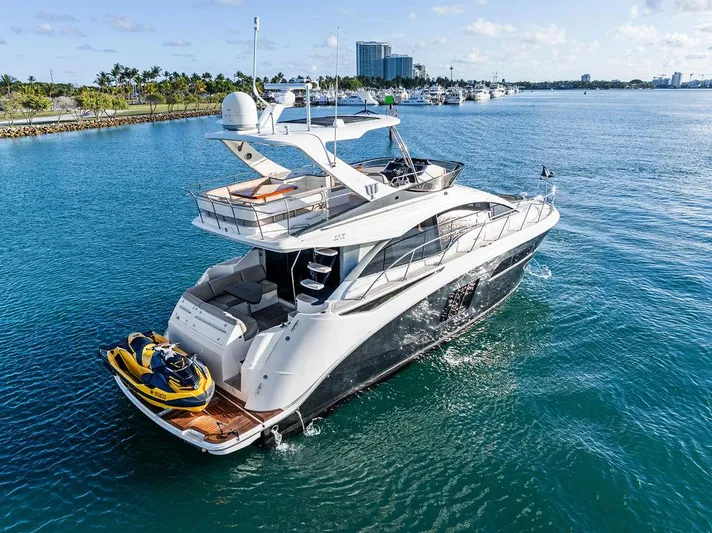  Yacht Photos Pics 2015 Sea Ray 510 Fly yacht cruising with jet ski on deck, in clear blue waters.