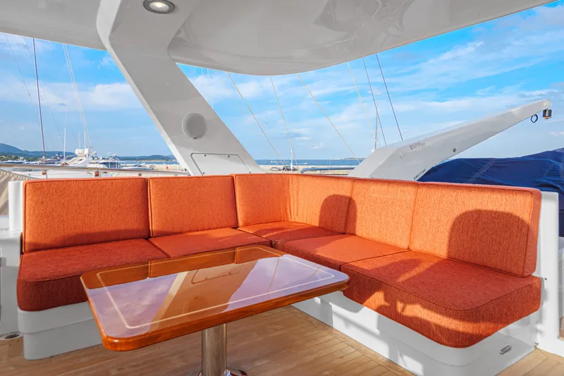Frivolous Yacht Photos Pics Luxurious 2019 Hunt Yachts motor yacht with orange seating and wooden table on deck.